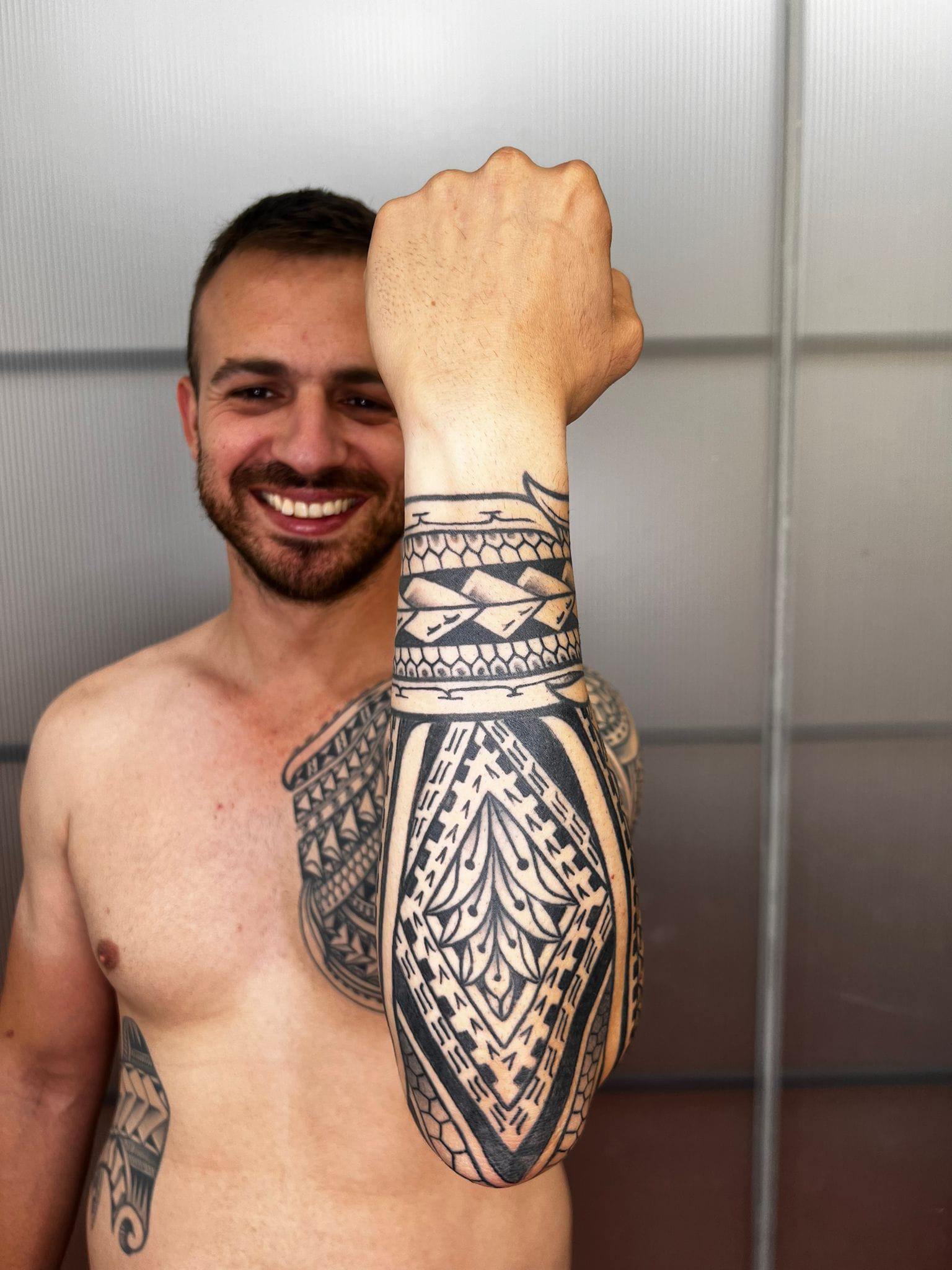 Tatuaje maorí en antebrazo con brazalete geométrico